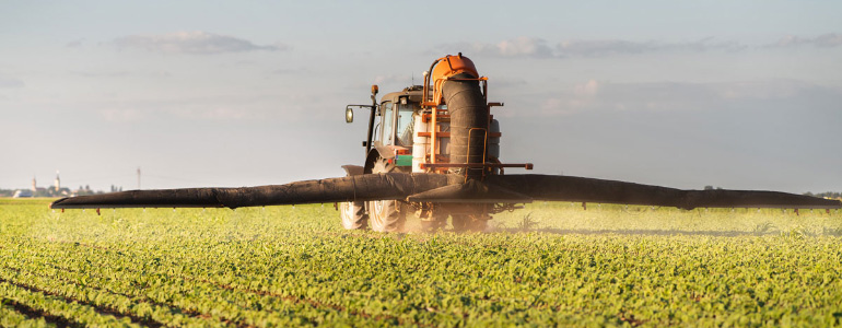Tractor spraying pesticides on soy field with sprayer in spring