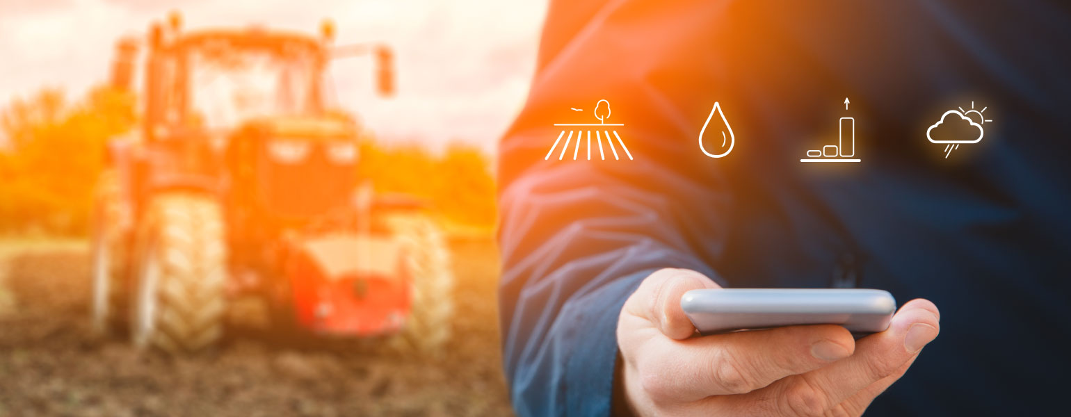 186879491_l Intelligent agriculture concept of farmer in field holding mobile device, with tractor in background
