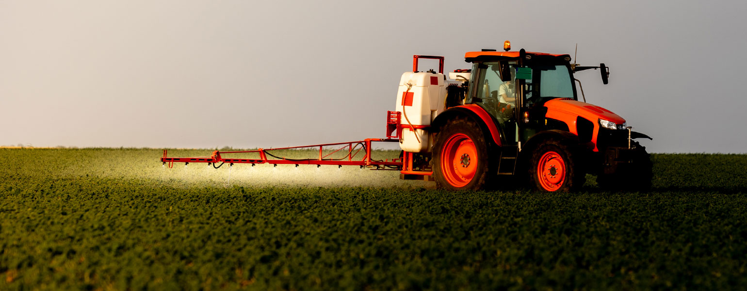 Tractor spraying pesticides on soybean field