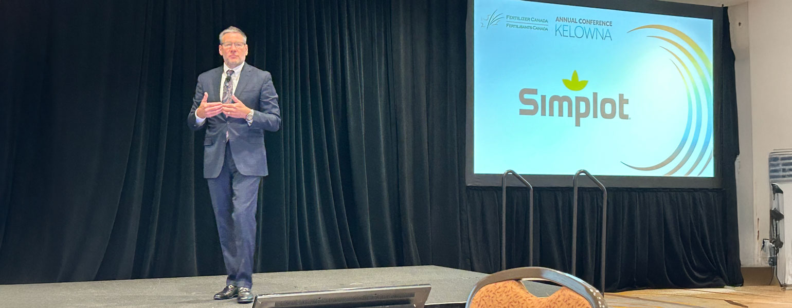 Garret Lofto on stage, with digital Simplot logo in background