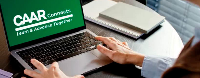 Laptop on table with CAAR logo on display on screen