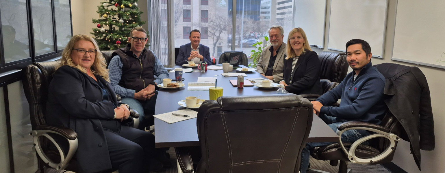 MP John Barlow sitting at boardroom table with Myrna Grahn, Tracey Shelton, Stan Loewen and Craig Senchuk